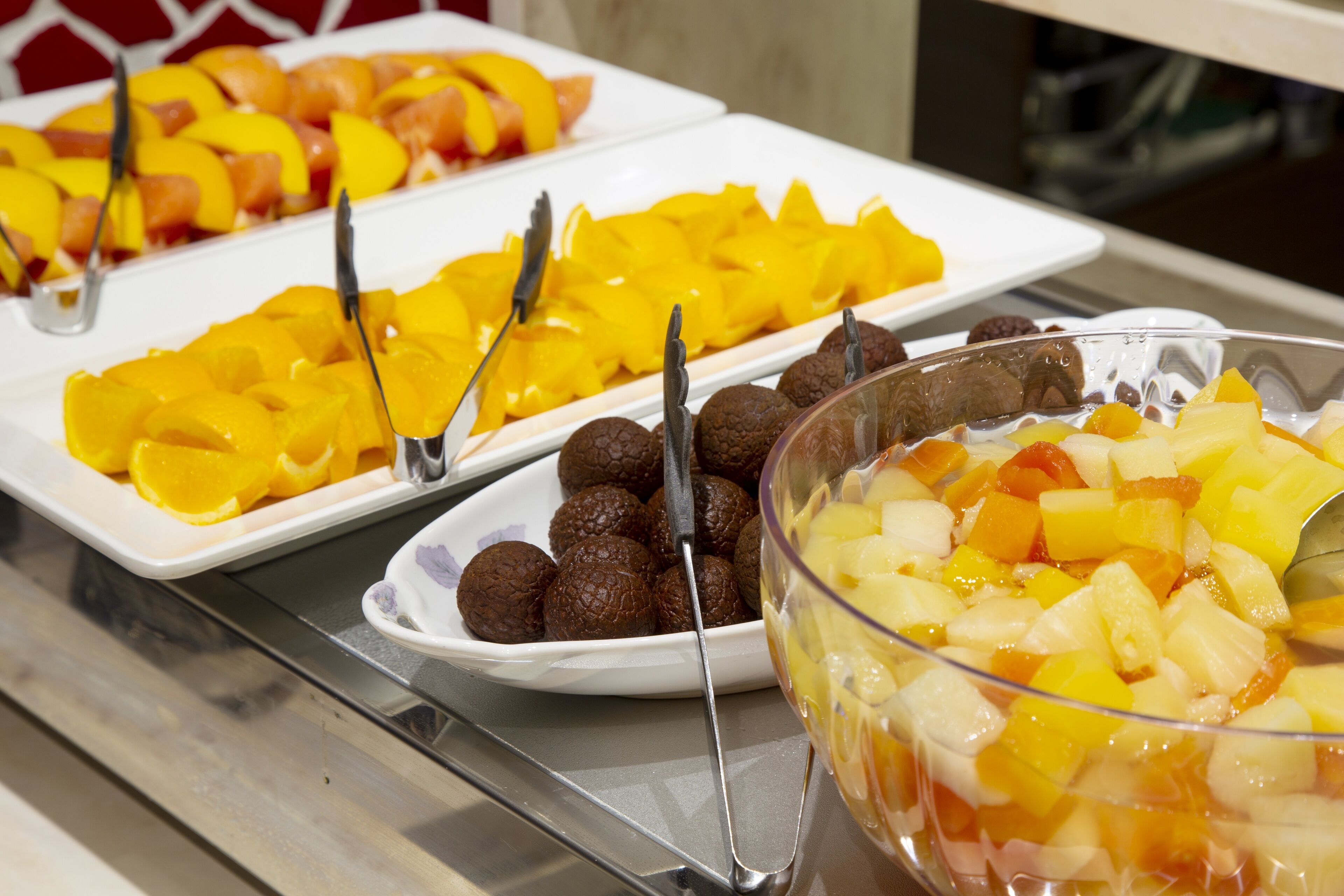 A buffet table with various fruit and dessert options.