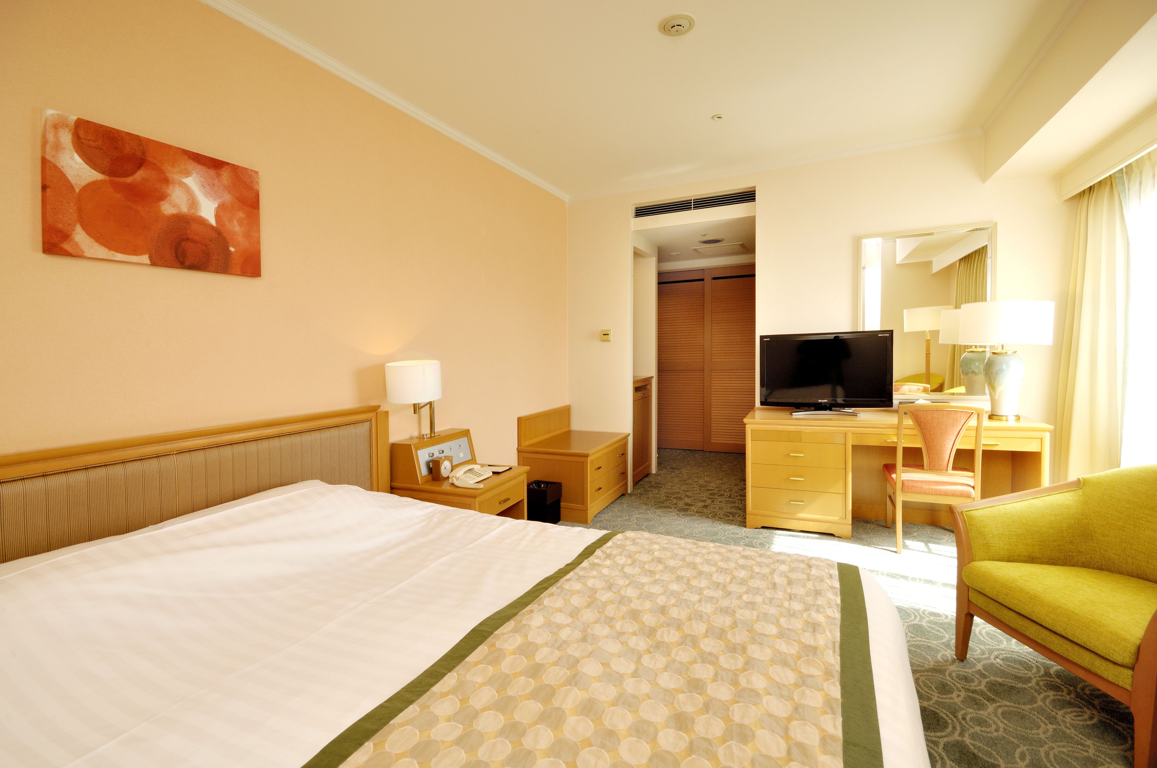 A hotel room with a bed, a desk with a computer, a television, and a chair.