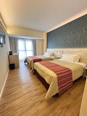 A hotel room with two beds, a flat-screen TV, a coffee maker, and a patterned wall. - Regente Palace Hotel (Buenos Aires)