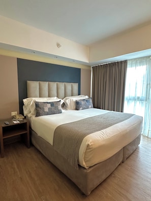 A hotel room with a large bed, a bedside table with a phone and papers, and a window with curtains. - Regente Palace Hotel (Buenos Aires)