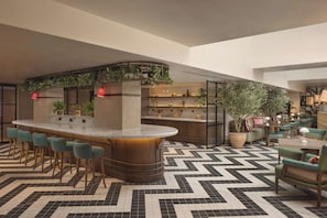 A bar area with a curved counter, bar stools, and shelves with decorative items.