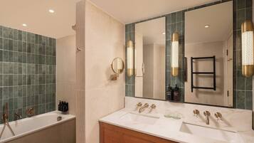 A modern bathroom with a bathtub, a vanity with a mirror, and a large mirror reflecting the room.