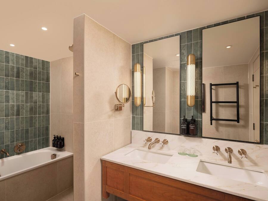 A modern bathroom with a bathtub, a vanity with a mirror, and a large mirror reflecting the room.