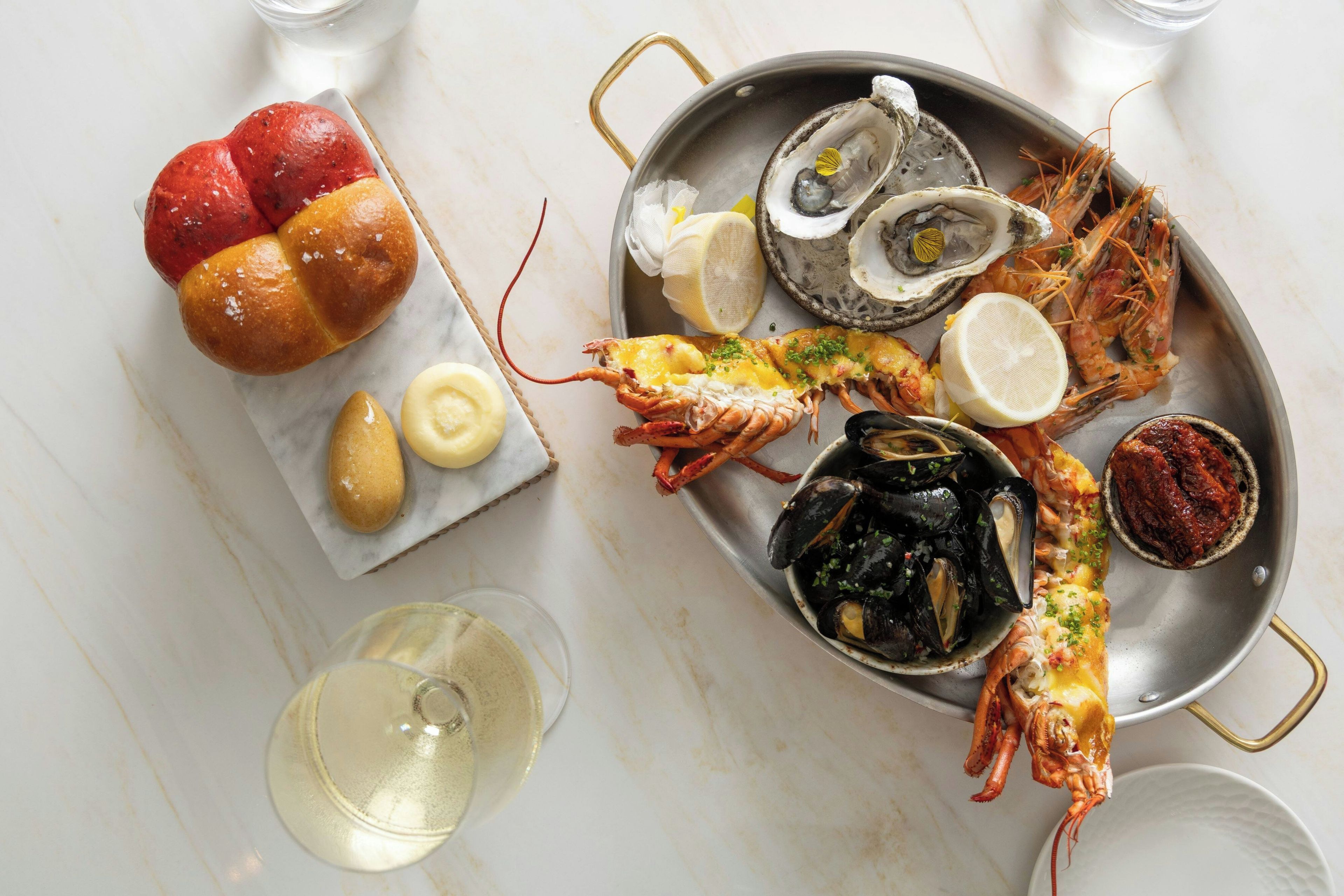 A seafood platter with various shellfish and a loaf of bread on a marble table.