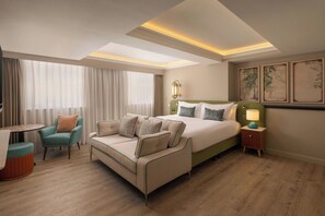 Una habitación de hotel con una cama, un sofá, una silla, una mesa y una mesita de noche.