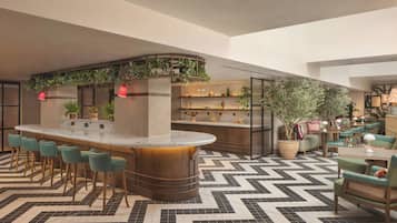 A bar area with a curved counter, bar stools, and shelves with decorative items.