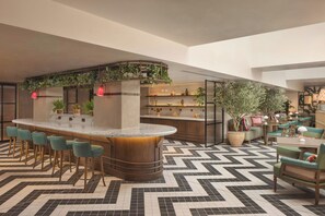 Un espace bar doté d’un comptoir incurvé, de tabourets de bar et d’étagères ornées d’objets décoratifs.
