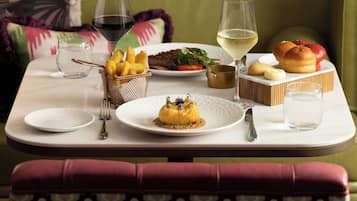 A dining table with a variety of dishes, glasses of wine, and a bench.