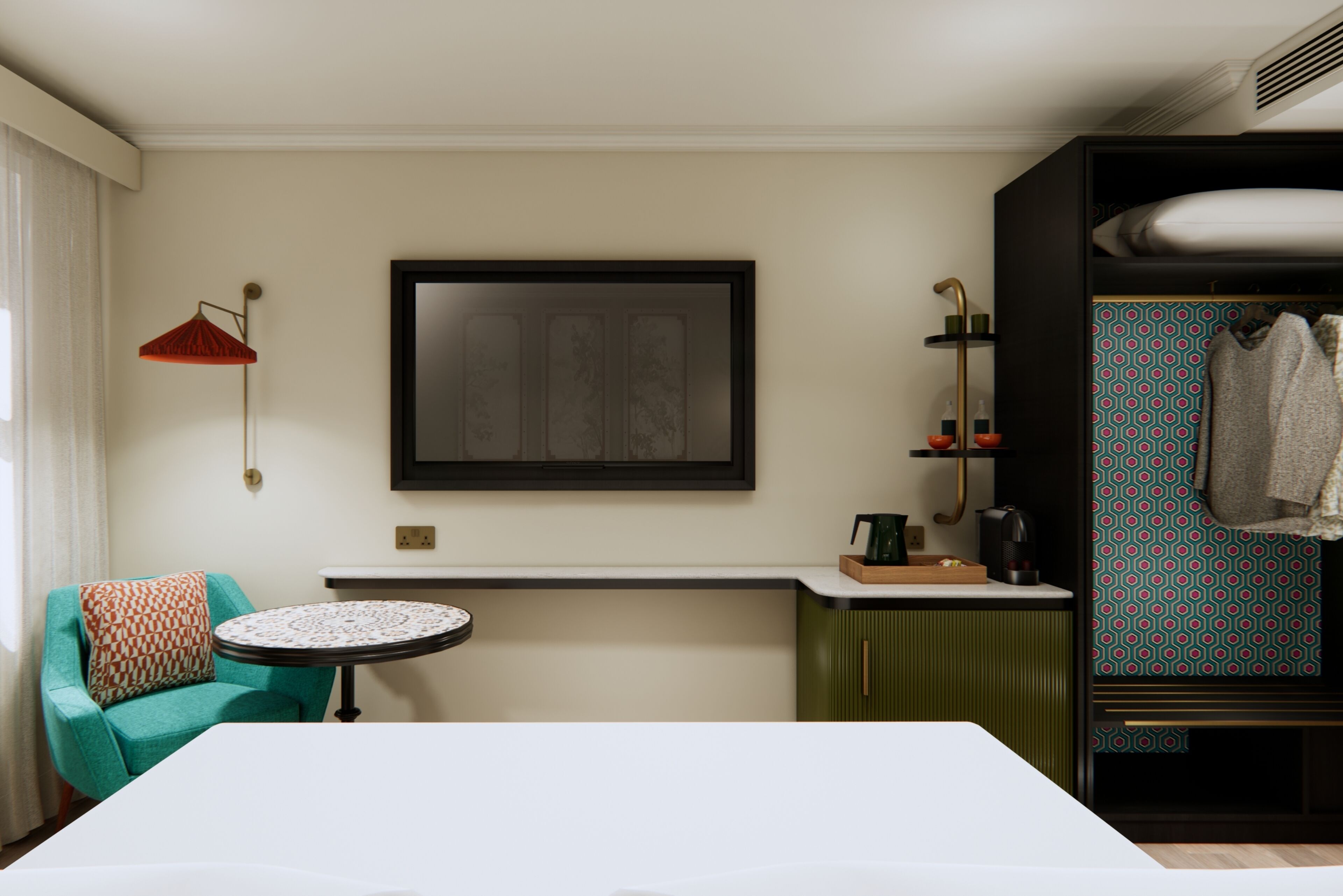 A hotel room with a bed, a round table, a chair, a red lamp, a framed artwork, a shelf with toiletries, and a patterned wall.