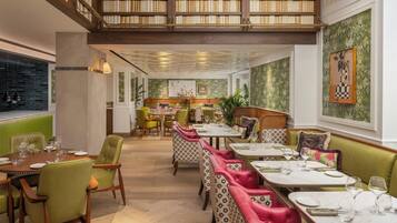 Ein Restaurant mit hohen Decken, Holzböschern und einer Mischung aus Sitzgelegenheiten, darunter Tische und Boxensitzplätze.