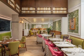 A restaurant with a high ceiling, wooden bookshelves, and a mix of seating including tables and booths. - Hyde & Seek, London Hyde Park, a Tribute Portfolio Hotel (London)