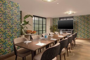 A conference room with a long table, chairs, a television, and decorative plants. - Hyde & Seek, London Hyde Park, a Tribute Portfolio Hotel (London)