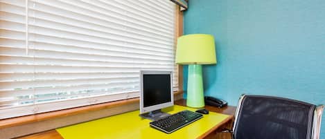 A room with a wooden desk, a computer, a lamp, and a chair.