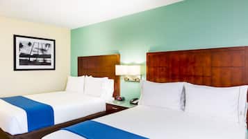 Habitación de hotel con dos camas, una mesita de noche con lámpara, un teléfono y un cuadro en la pared.
