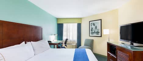 Quarto de hotel com uma cama grande, uma escrivaninha com cadeira, televisão e um armário.