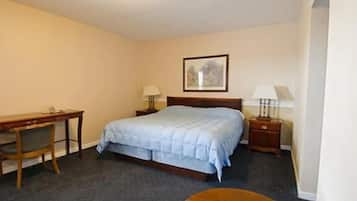 A hotel room with a bed, a desk, two bedside tables, and a chair.