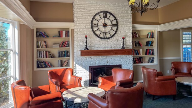 Una biblioteca con sillones de cuero, chimenea y estanterías.