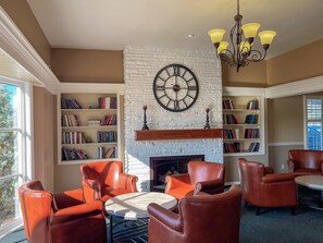 A library with leather chairs, a fireplace, and bookshelves. - Alpine Inn Rockford (Rockford)