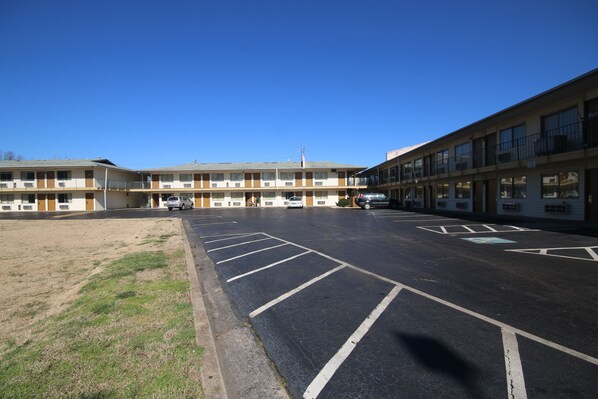 A motel with a parking lot and a building with multiple floors and balconies.