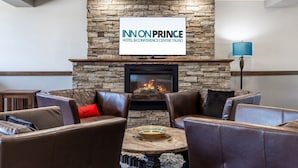 A lounge area with leather sofas, a stone fireplace, and a mounted sign reading "INN ON PRINCE HOTEL & CONFERENCE CENTRE TRURO".