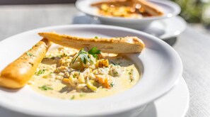 A bowl of creamy soup with breadsticks and a garnish, served on a white plate. - Inn on Prince Hotel & Conference Centre, an Ascend Collection Hotel (Truro)