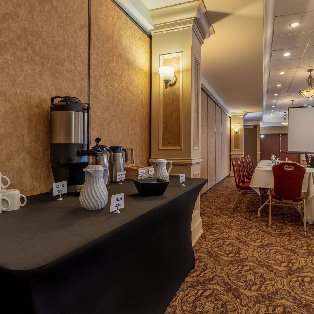 Habitación de hotel con estación de café, jarra de crema y una pizarra.