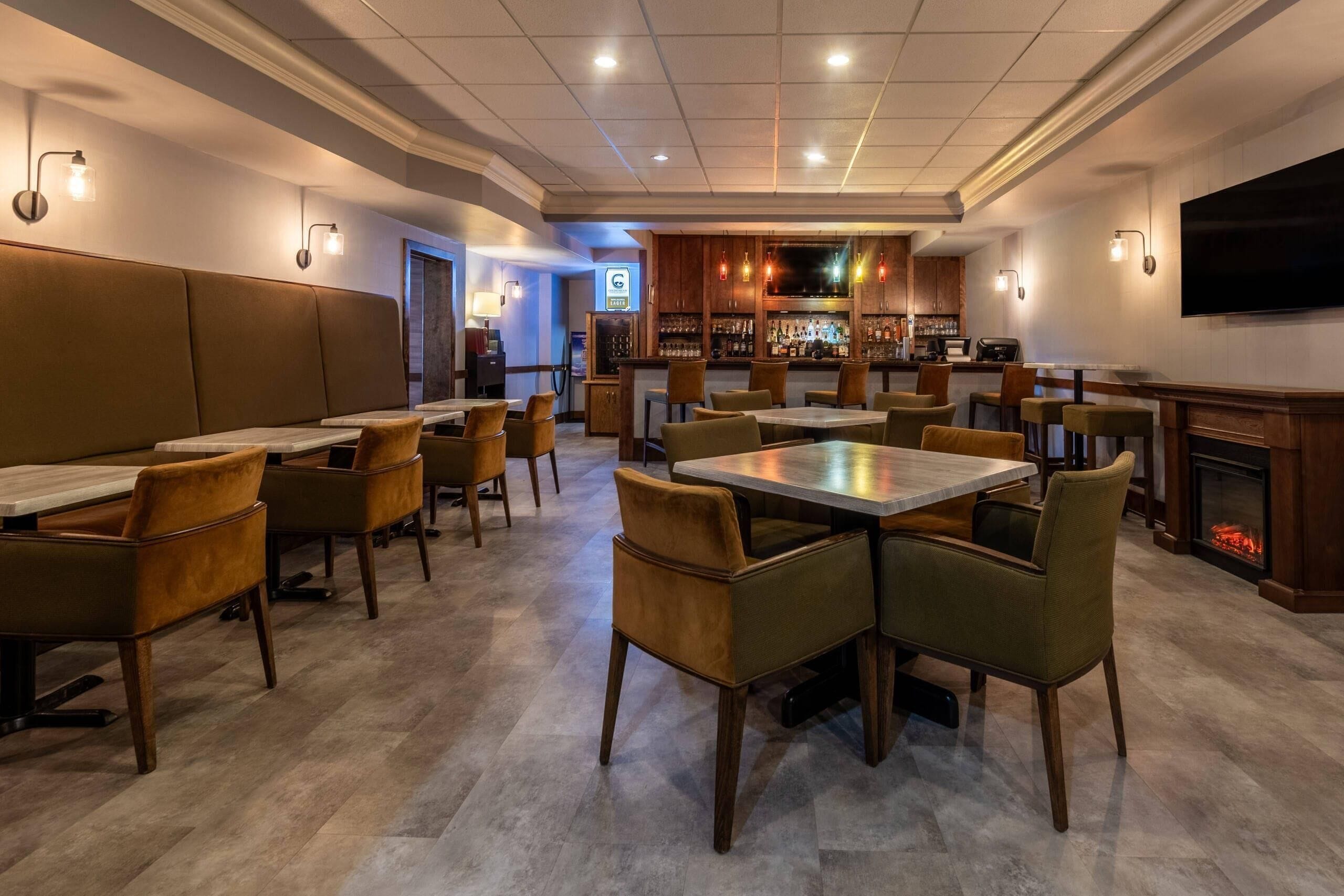 Ein Restaurant mit Sitzecken, Tischen, Stühlen, einer Bar und einem Kamin.