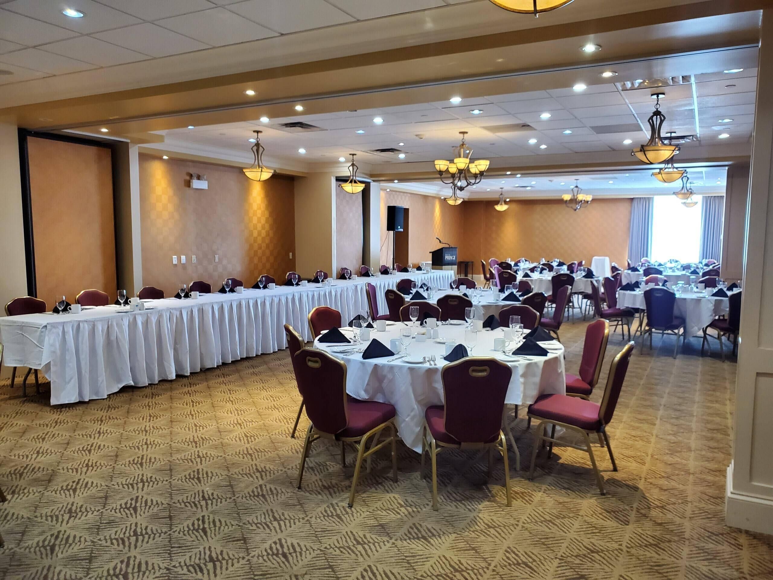 A conference room with multiple tables and chairs, a podium, and ceiling lights.