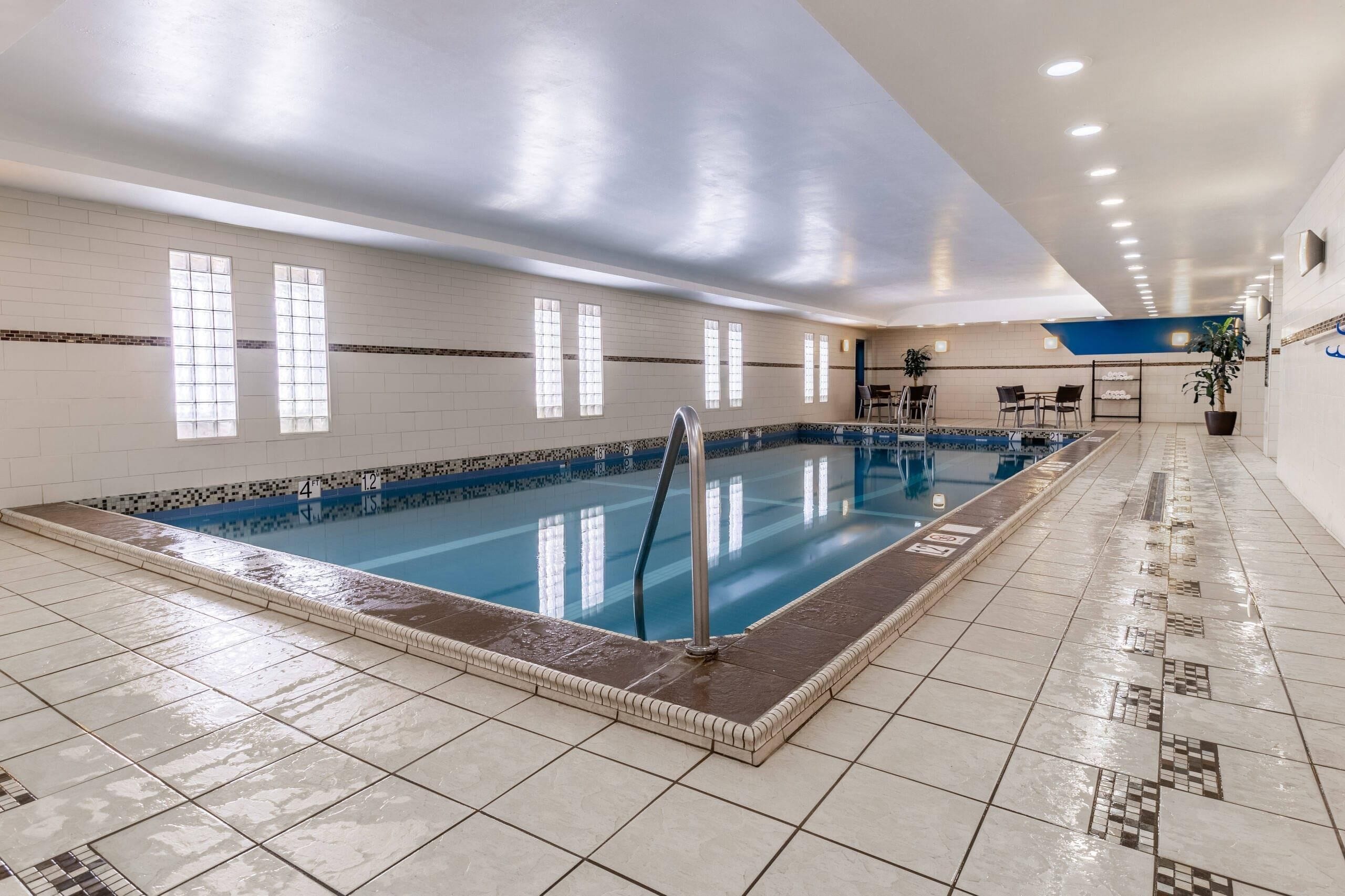 An indoor swimming pool with tiled walls, a blue pool, and a tiled floor.