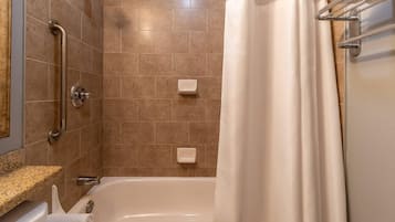 Ein Badezimmer mit Badewanne, Haltegriffen und einer Duschvorhang.