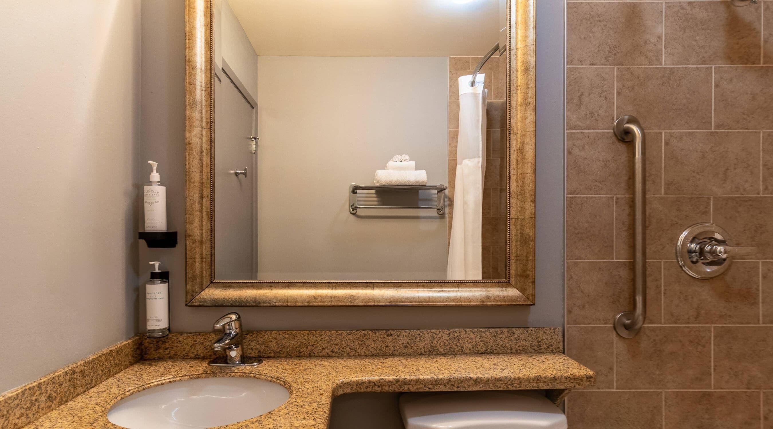 A bathroom with a sink, mirror, and shower.