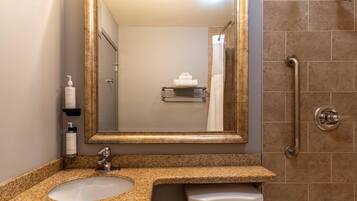 A bathroom with a sink, mirror, and shower.