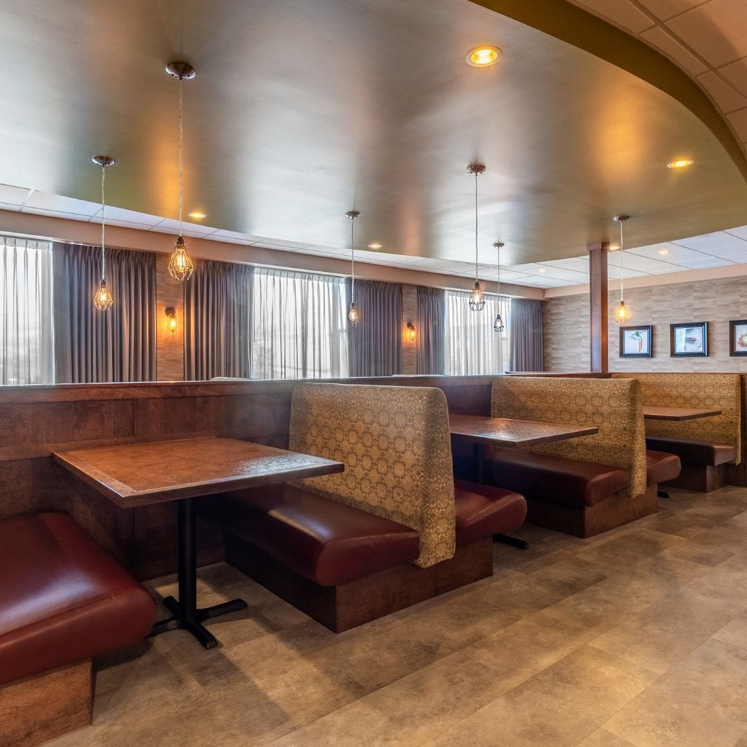 A restaurant interior with booth seating, pendant lighting, and a tiled floor.