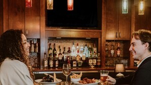 A bar area with wooden cabinets, bottles, and a television.