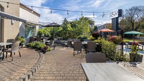 An outdoor patio area with brick flooring, outdoor seating, and string lights.