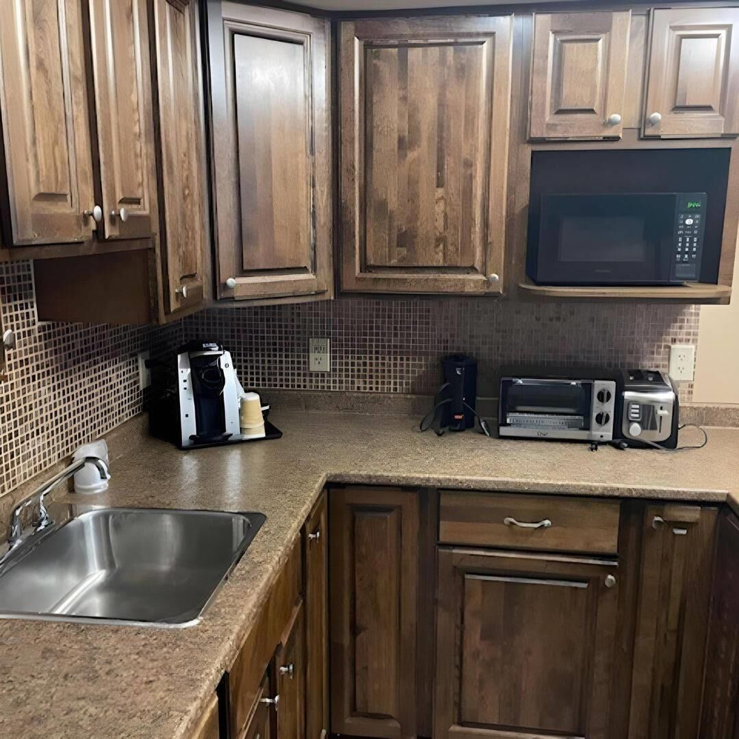 A kitchen with wooden cabinets, a microwave, a toaster, and a coffee maker.