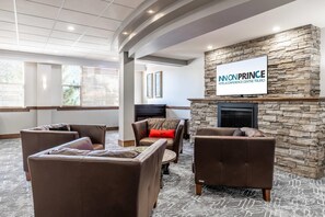 A lobby with brown leather sofas, a stone fireplace, and a television displaying 'INONPRINCE HOTEL & CONFERENCE CENTRE TRURO.' - Inn on Prince Hotel & Conference Centre, an Ascend Collection Hotel (Truro)