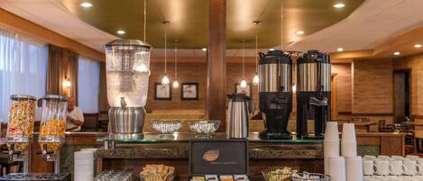 A hotel breakfast bar with a coffee machine, tea kettle, cereal dispensers, and a tea display.