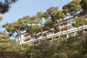 Un hotel de varios pisos con balcones y un paisaje verde y exuberante.