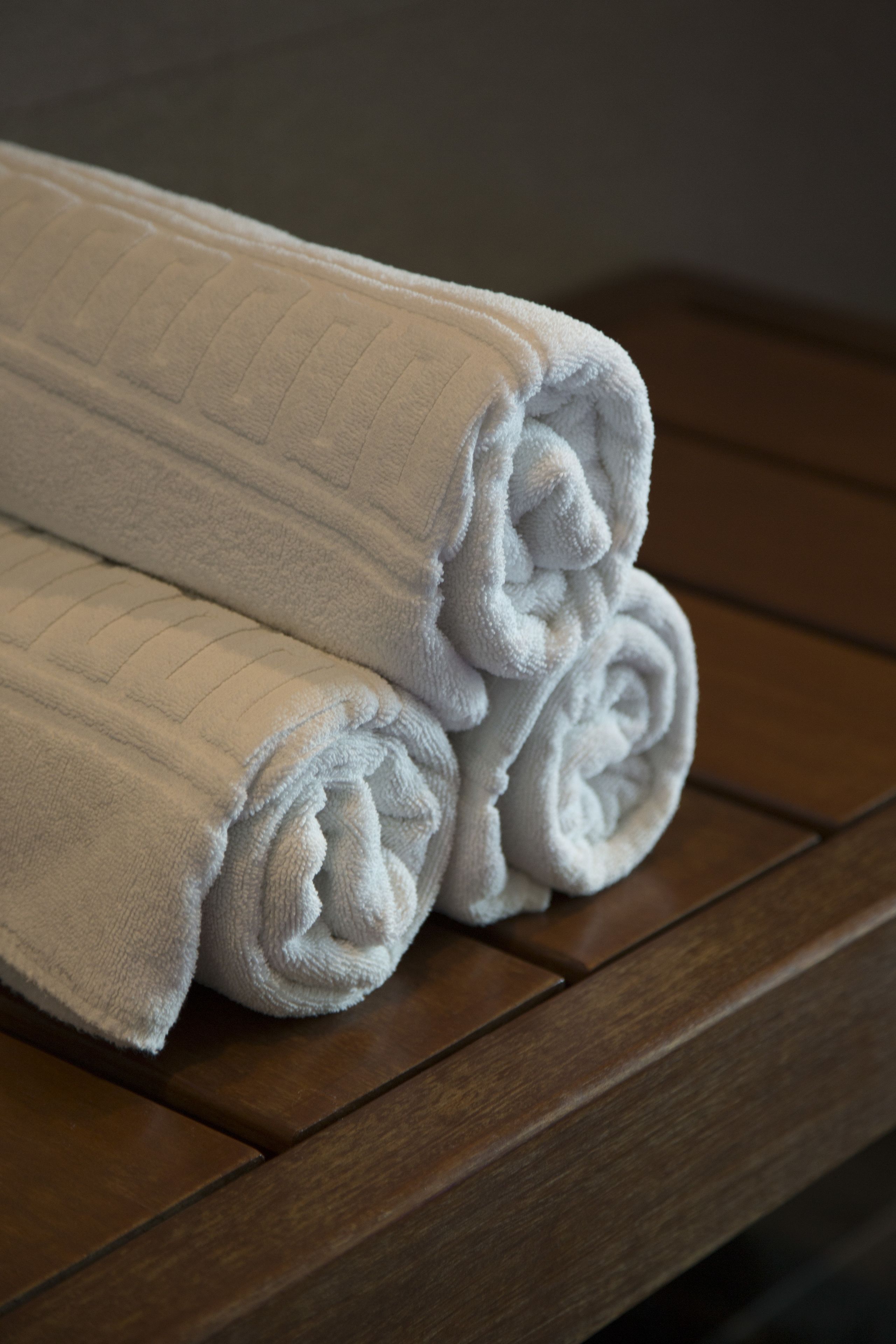 A stack of white towels on a wooden surface.