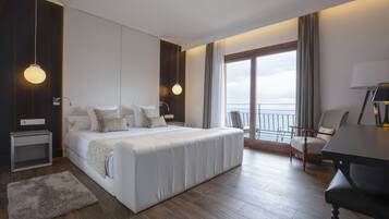 Habitación de hotel moderna con una cama grande, un escritorio y un balcón con vistas.