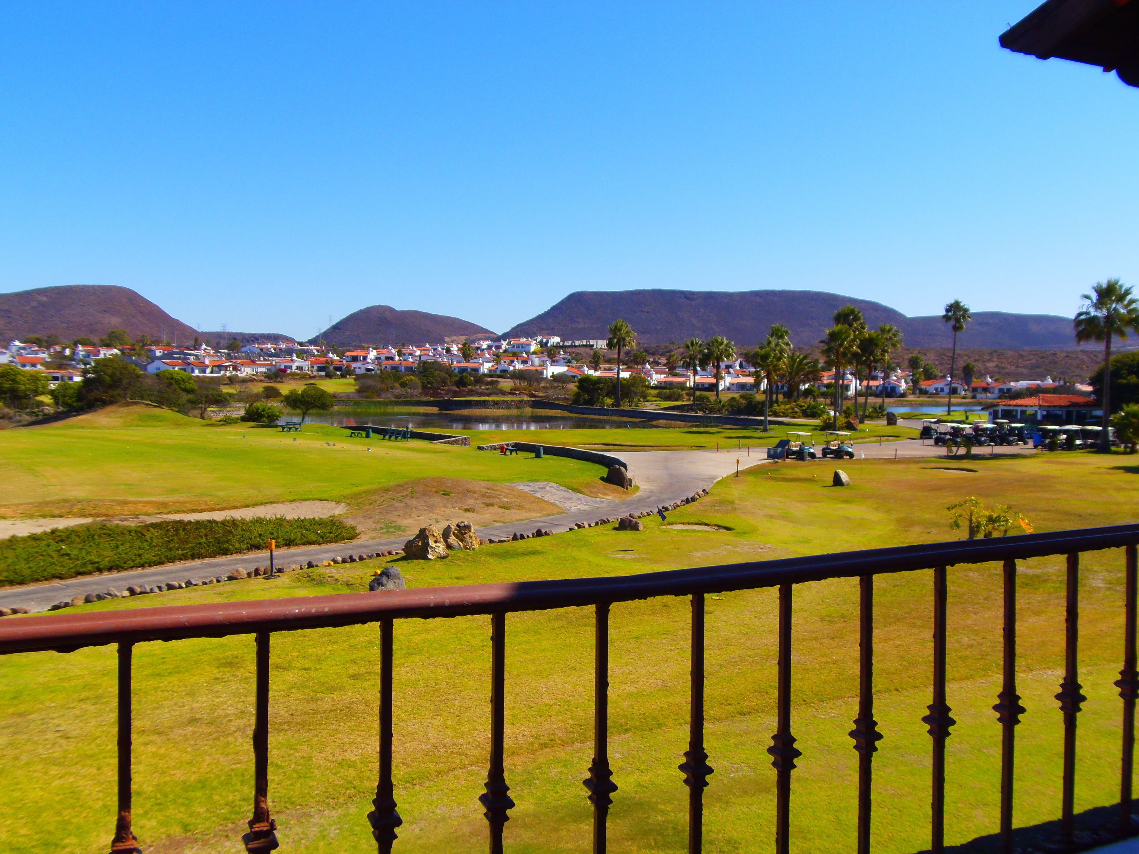 Un parcours de golf offrant une vue sur une ville et, au loin, sur des montagnes.