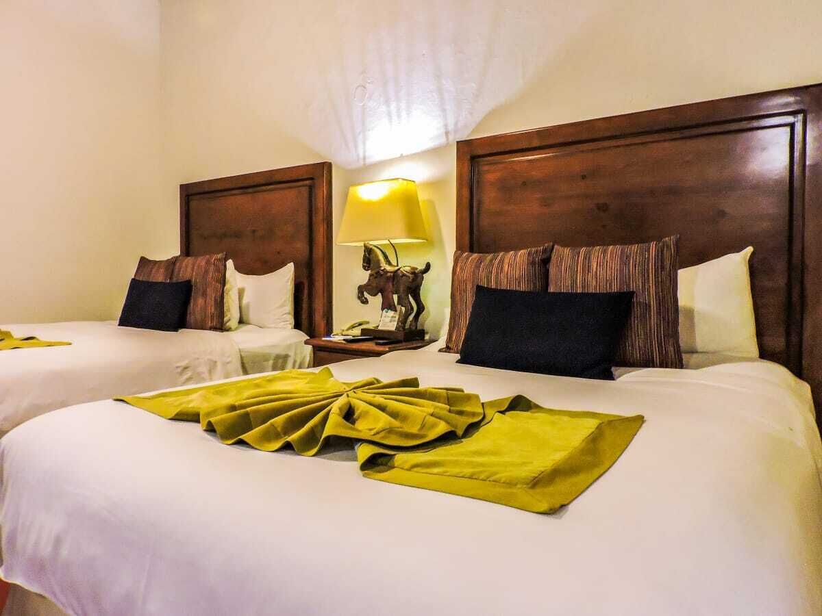 A hotel room with two beds, a nightstand with a lamp, and a decorative horse statue.
