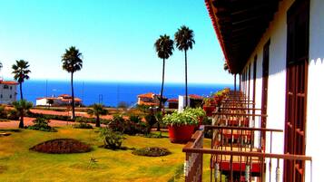 Enjoy the serene ocean views from this balcony overlooking a beautifully maintained garden.