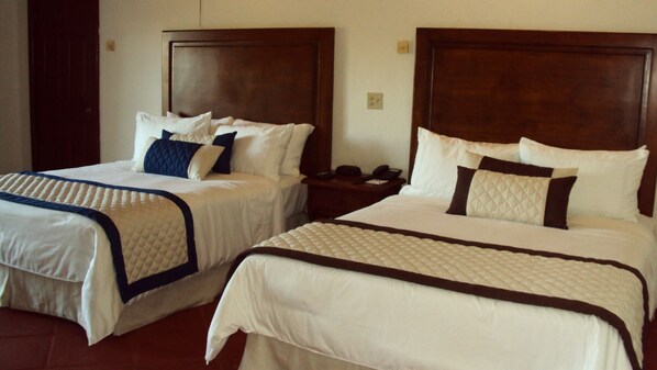 Two double beds with wooden headboards, white bedding, and a quilted blanket. - Hacienda Bajamar Golf Resort (Salsipuedes)