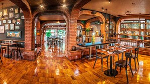 A restaurant with wooden floors, brick arches, and a bar area with a view of the outdoors.