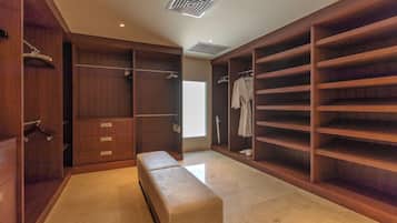 A walk-in closet with wooden shelving, a bench, and a large mirror.