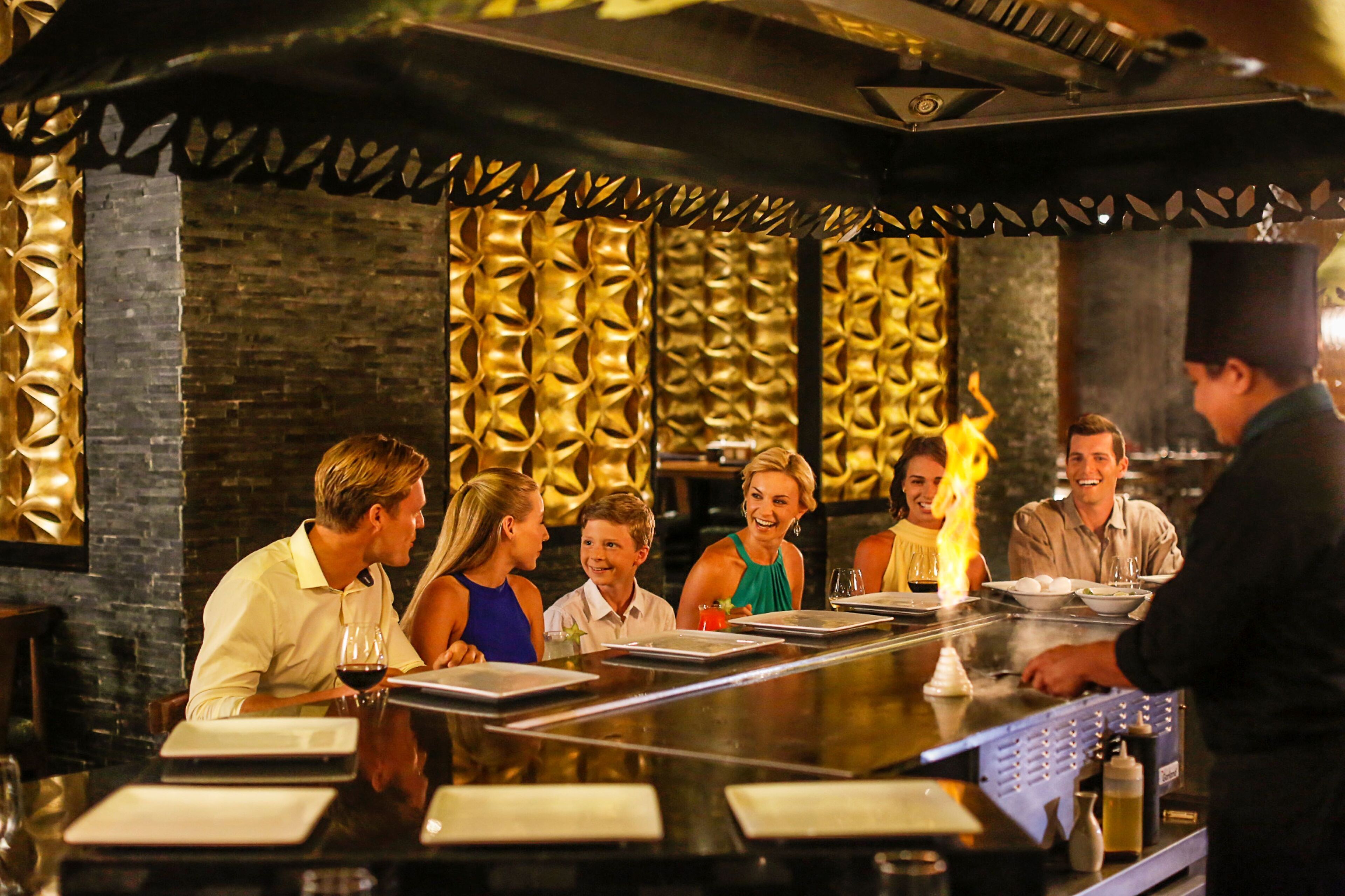 Zona de bar amb una barra llarga, un barman i diversos clients asseguts.