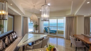 Una habitación de hotel moderna con comedor, zona de estar con vista al océano y balcón con vista al mar.