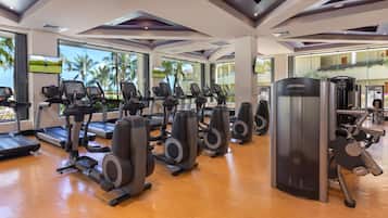Une salle de sport équipée de tapis de course, de vélos elliptiques et d’appareils de musculation.